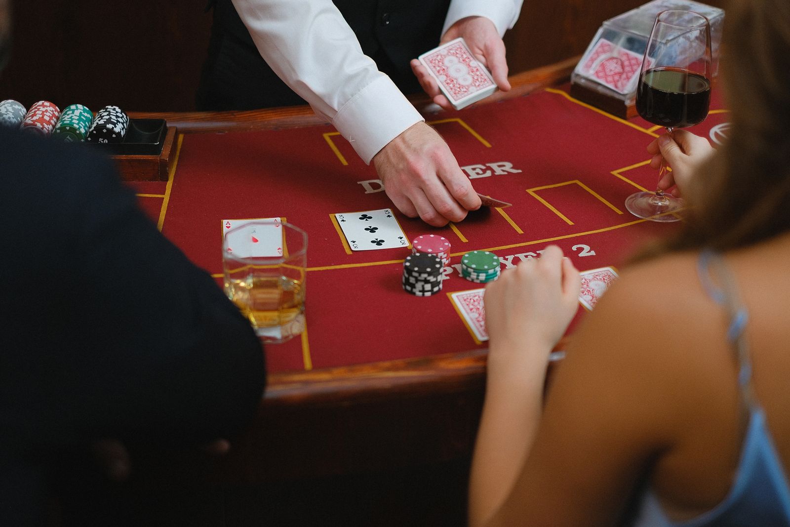 Guests playing cards with a dealer at a red casino table